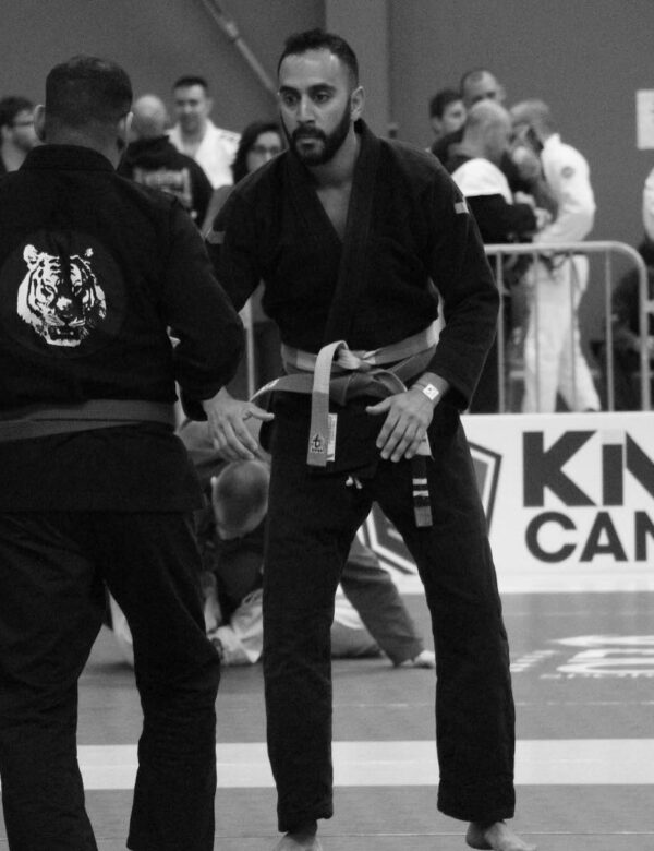 Professor Kale Harvey facing an opponent during a Brazilian Jiu-Jitsu gi competition match.