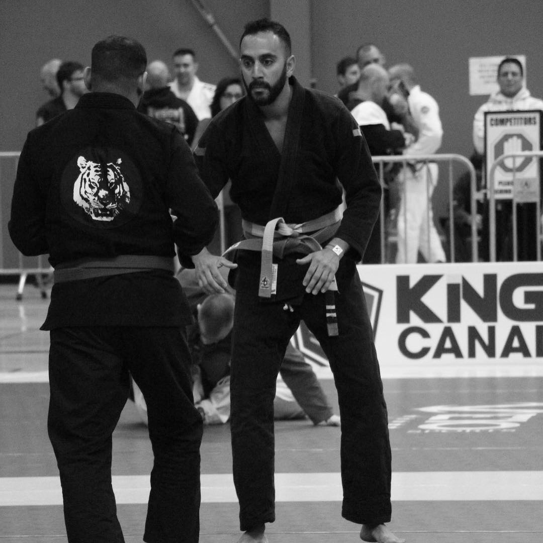 Professor Kale Harvey facing an opponent during a Brazilian Jiu-Jitsu gi competition match.