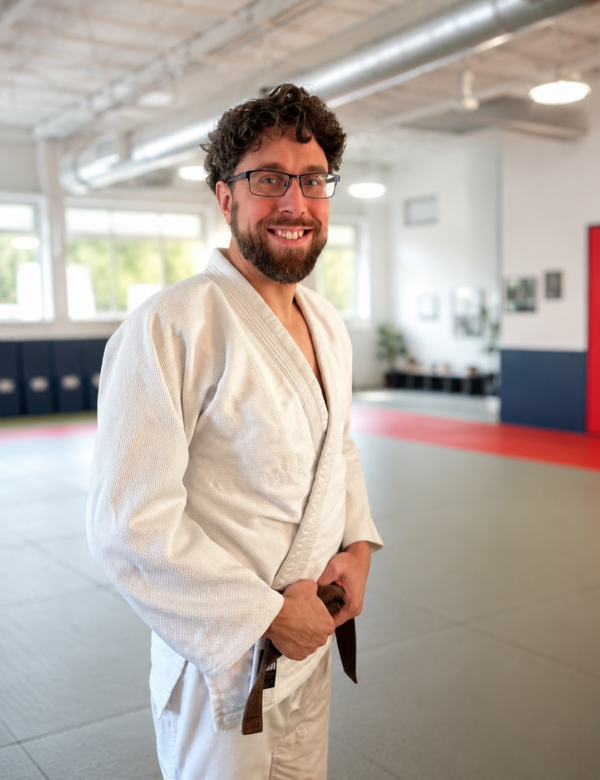 Judo coach Nick Prince smiling in a white gi inside the True North Martial Arts dojo.