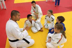 Sensei Kevin giving instructions to a group of young Judo athletes during a tournament.