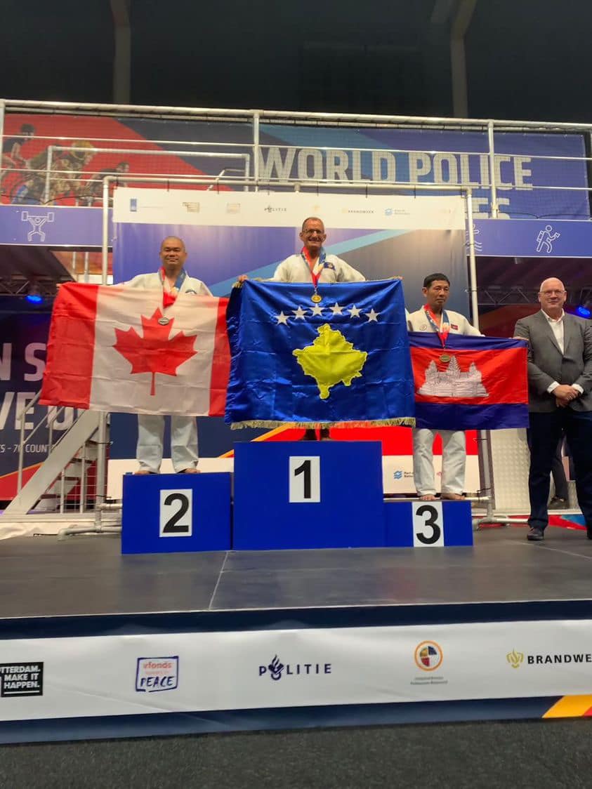 Sensei Kevin standing on the silver-medal podium with the Canadian flag at the World Police and Fire Games.