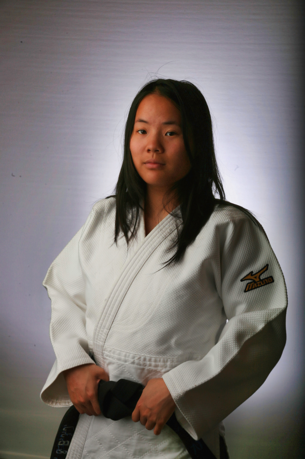 Sensei Rhiannon Lau wearing a white Judo gi and black belt for her coaching profile.