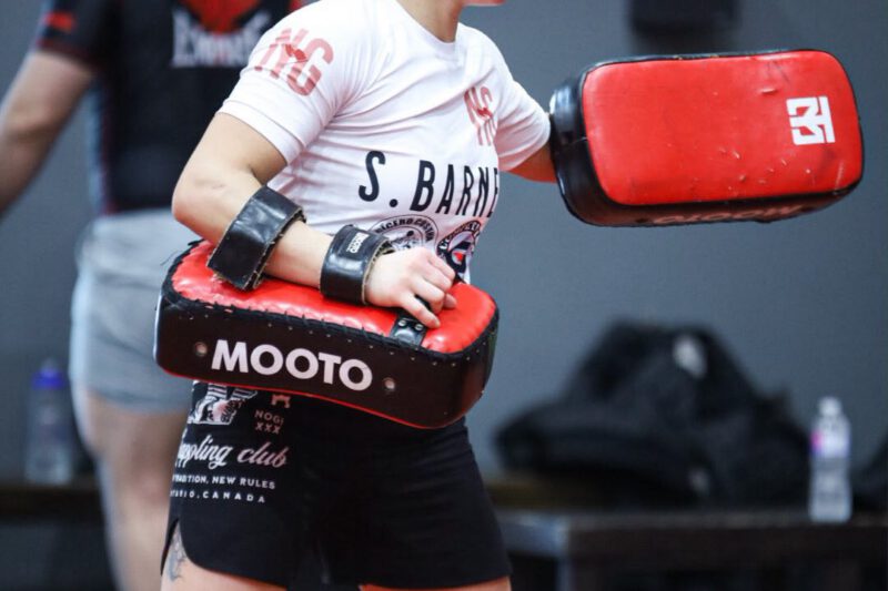 Professor Shiv Barnes holding kickboxing pads during a striking training session.