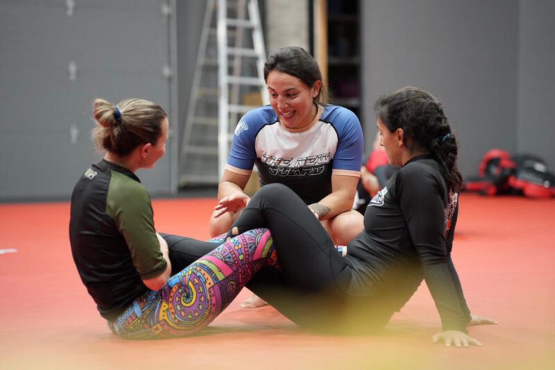 Professor Shiv Barnes coaching two women during a women’s-only no-gi Brazilian Jiu-Jitsu class.